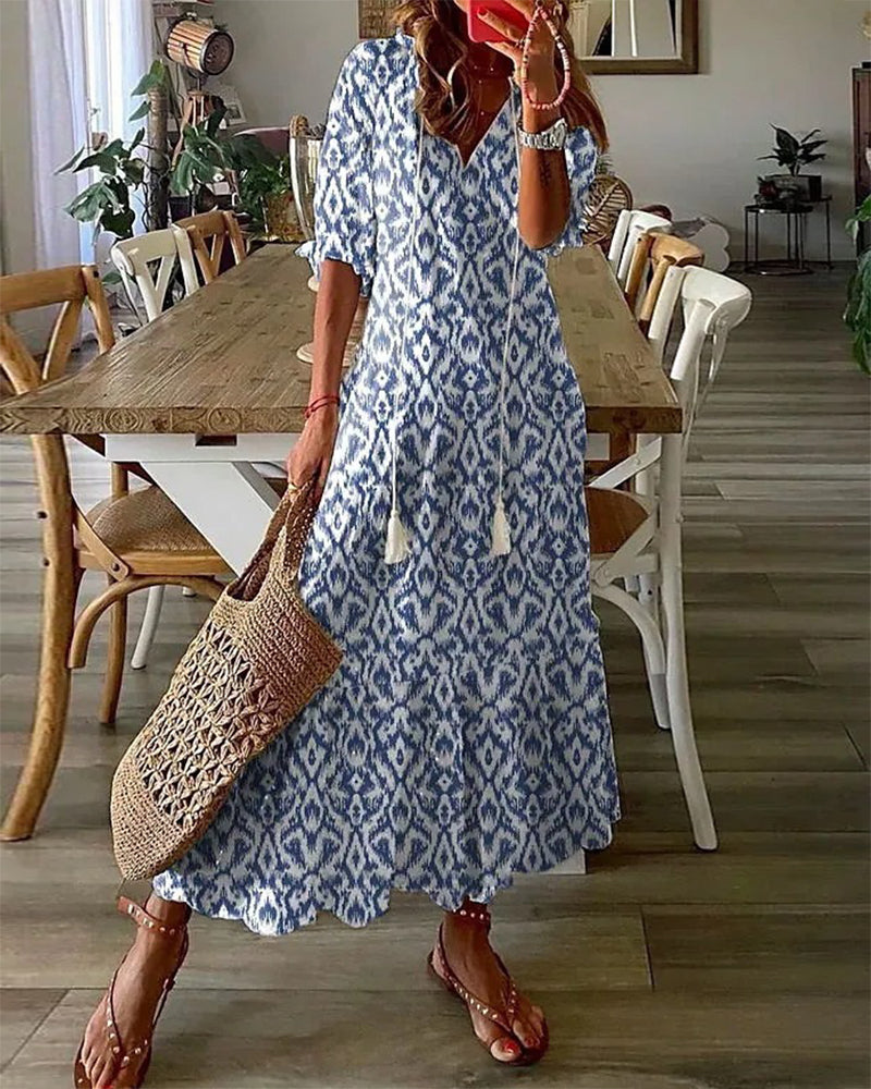 Woman wearing the Jacqueline™ boho maxi dress with fringe details and a V-neckline, relaxed in a warm outdoor setting.