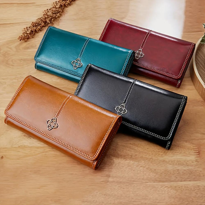 A woman holding a long flap-over wallet, tucking a card into its slot.