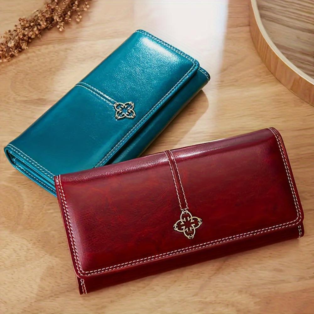 A woman holding a long flap-over wallet, tucking a card into its slot.