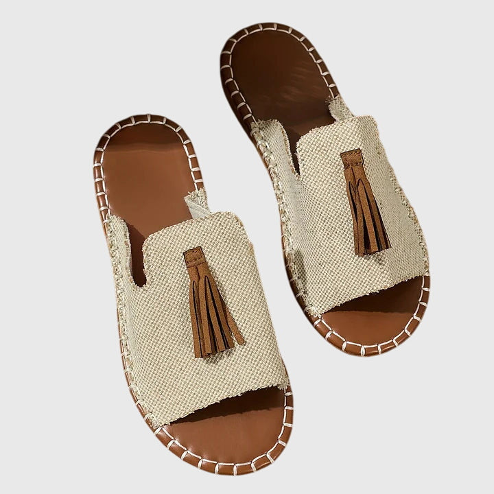 A woman wearing colourful patterned boho slides with tassel details on a holiday day out.