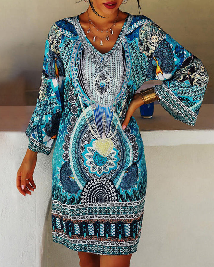 Woman wearing the Lucie boho print dress with bell sleeves, smiling outdoors on a bright day.