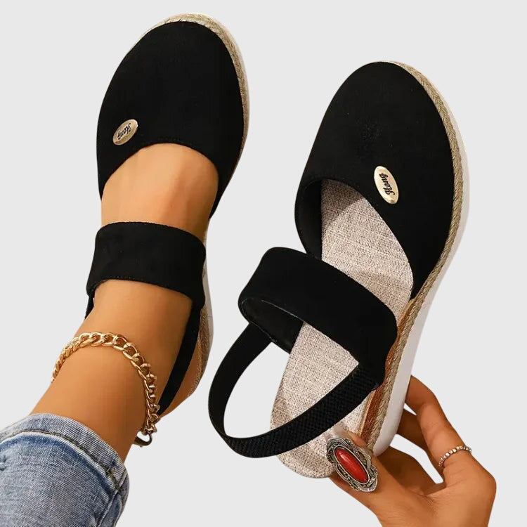 Black closed-toe wedge espadrilles with a wide stretch strap and a braided-trim platform wedge.