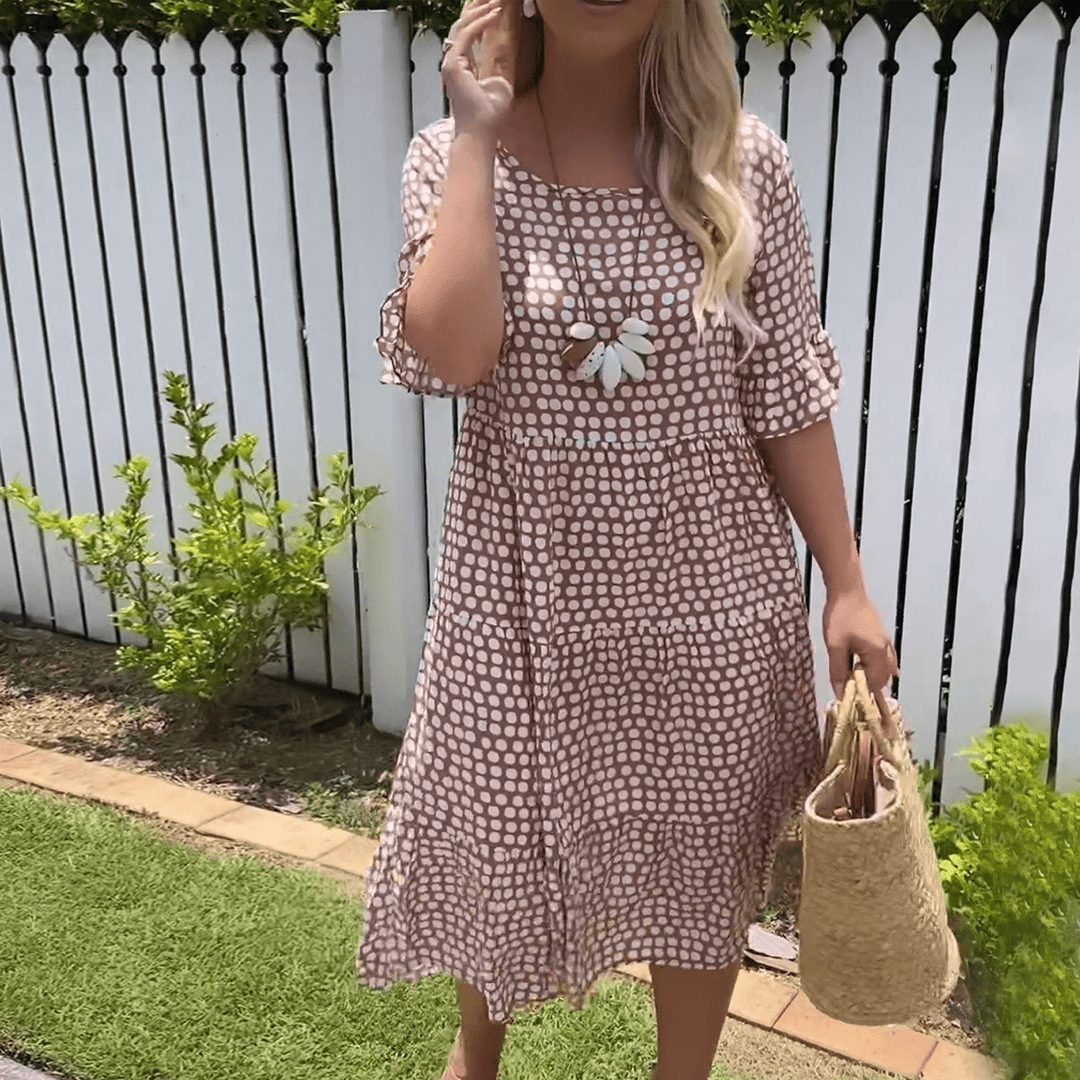 A woman wearing the Tammy short sleeve midi dress with a flowing skirt on a warm day.