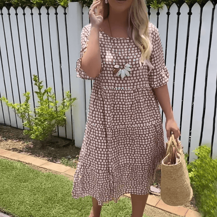 A woman wearing the Tammy short sleeve midi dress with a flowing skirt on a warm day.