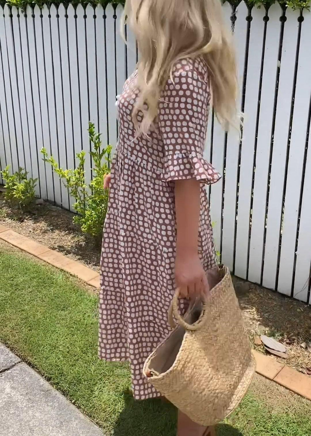 Woman wearing the Natalie™ polka dot midi dress with short sleeves, relaxed and smiling in a summer setting.