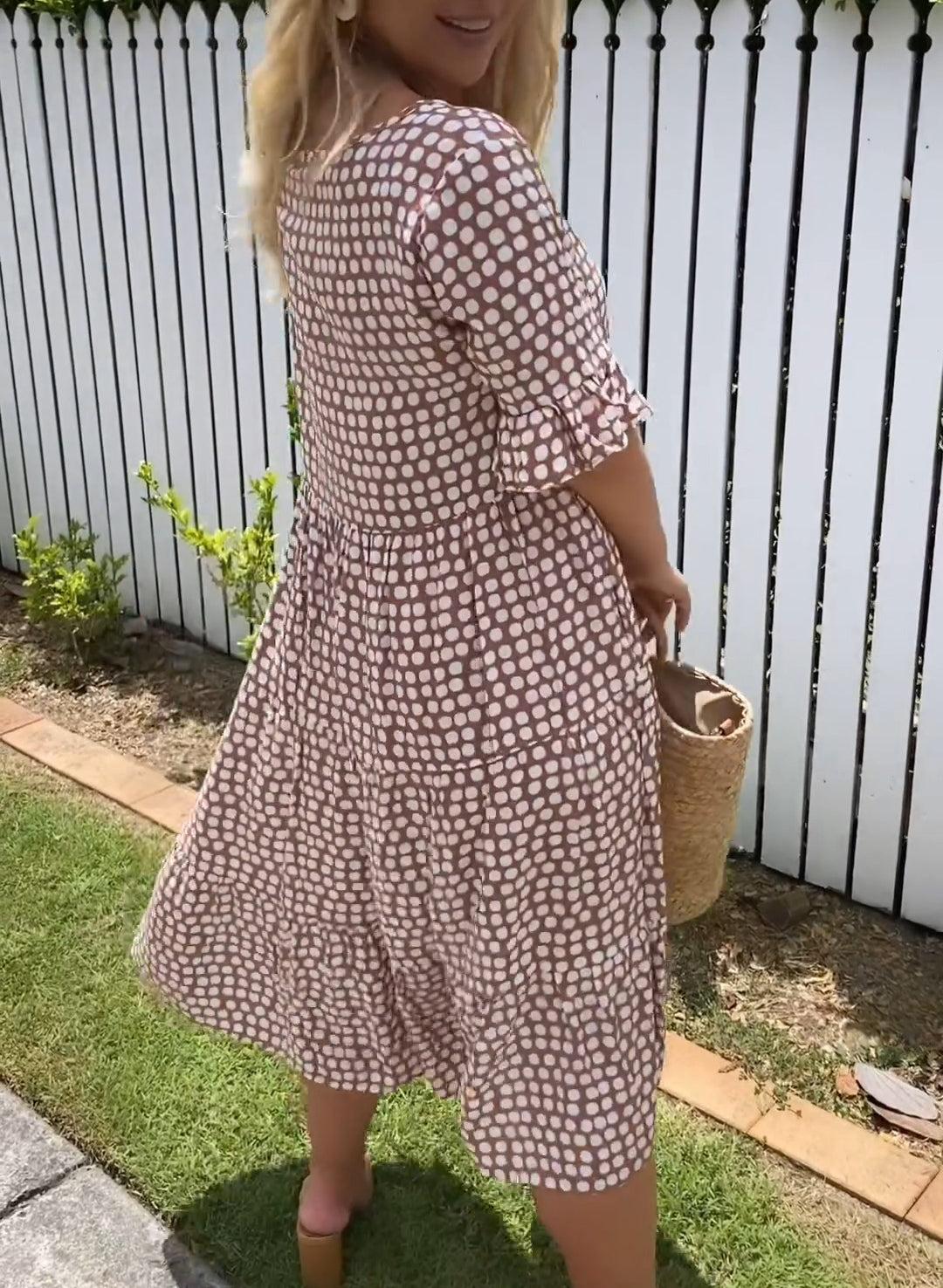 A woman wearing the Tammy short sleeve midi dress with a flowing skirt on a warm day.