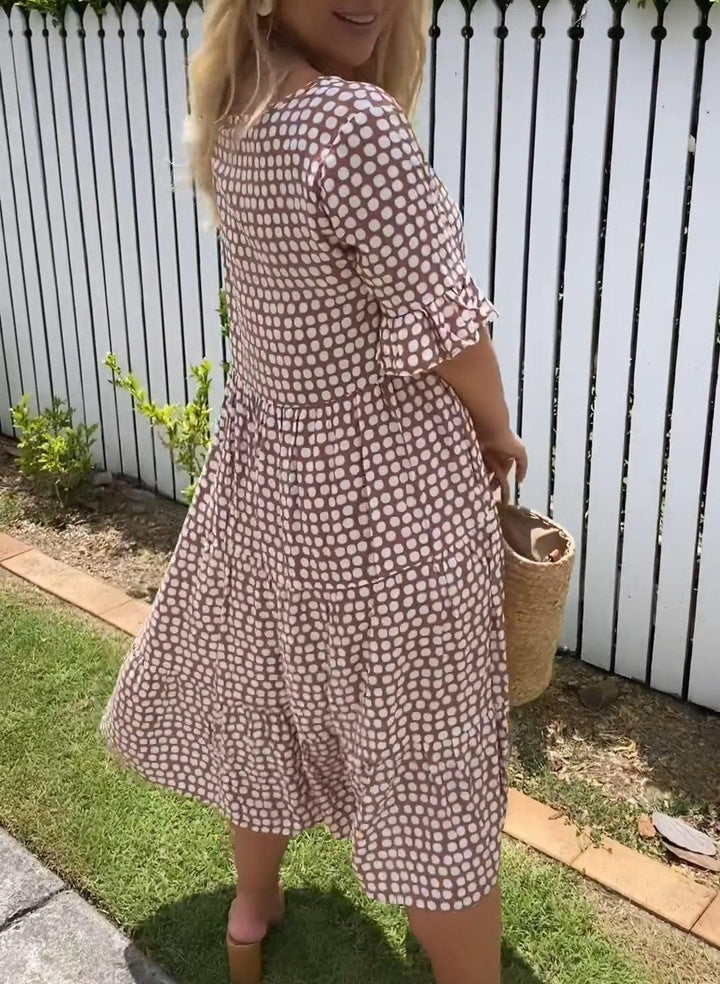 A woman wearing the Tammy short sleeve midi dress with a flowing skirt on a warm day.
