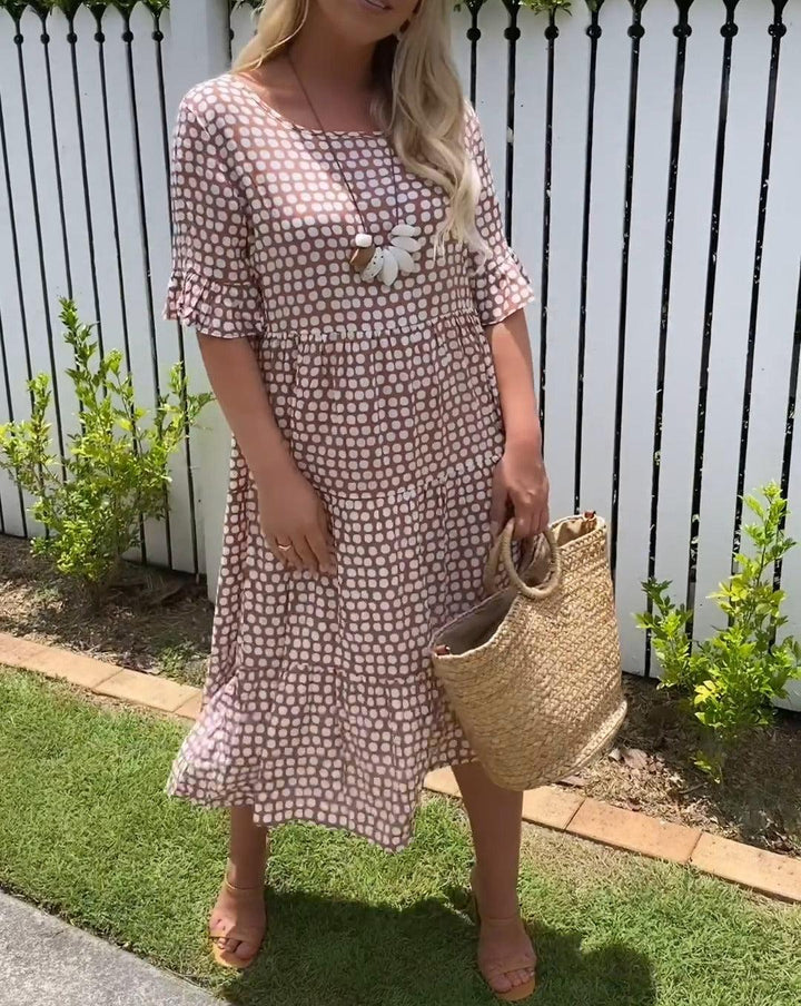 Woman wearing the Natalie™ polka dot midi dress with short sleeves, relaxed and smiling in a summer setting.