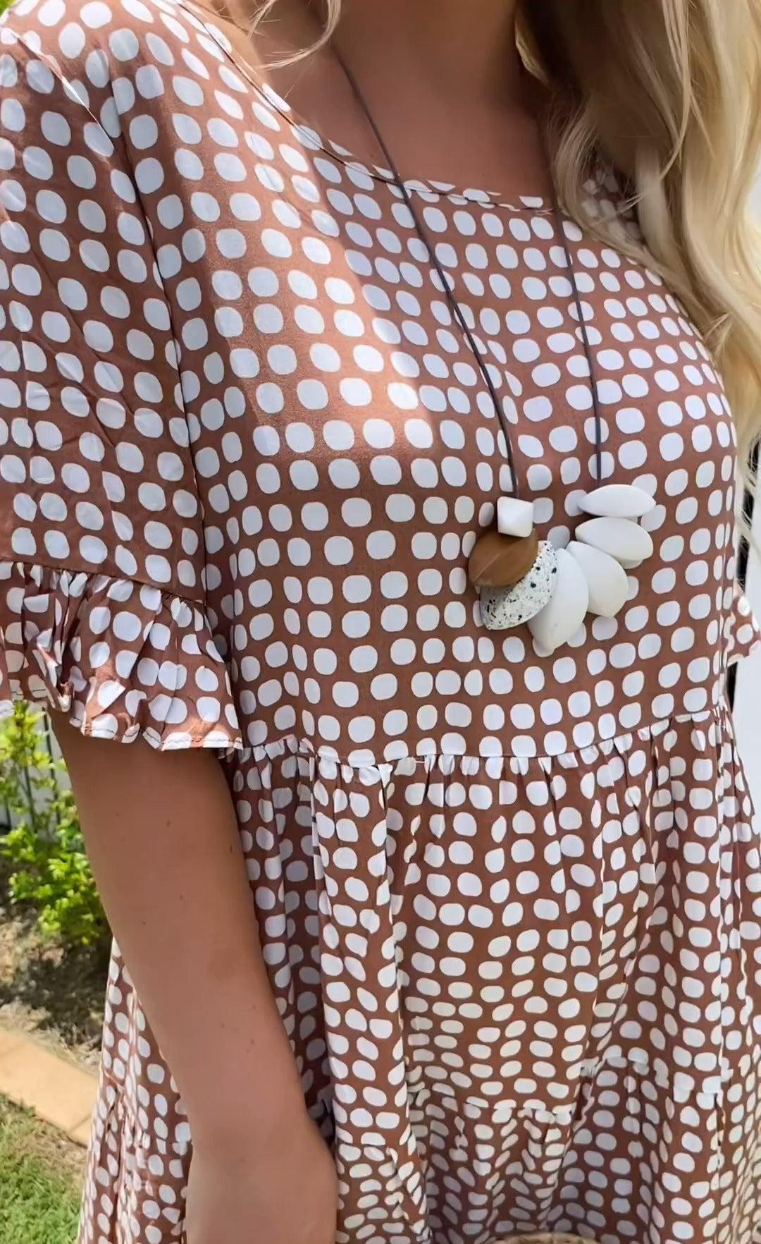 Woman wearing the Natalie™ polka dot midi dress with short sleeves, relaxed and smiling in a summer setting.