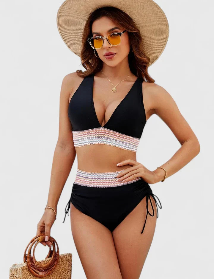 A woman wearing an elegant matching bikini set with a bold print, relaxed and confident on the beach.