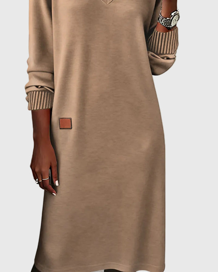 Woman wearing the Susan flowing elegant dress in beige, standing relaxed and smiling.