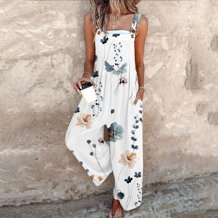 A woman wearing elegant black overalls with a single large cream bloom and adjustable straps.