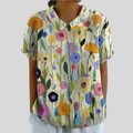 A woman in a blossom-print top with an elegant collar, dressed with easy confidence.