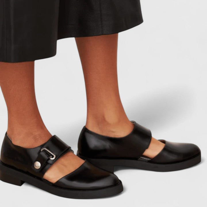 A woman wearing black Mary Jane shoes with an adjustable strap, comfortable on a busy day.