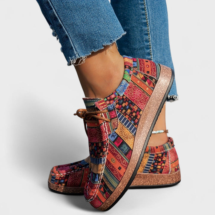 A woman wearing lace-up sneakers in a bold multicolour tribal print on a lightweight platform sole