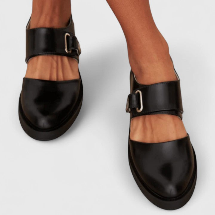 A woman wearing black Mary Jane shoes with an adjustable strap, comfortable on a busy day.