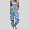 A woman wearing light blue overalls printed with cheerful little bees and fine dots, with adjustable straps.