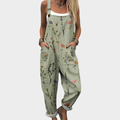A woman wearing soft sage green overalls scattered with delicate wildflowers, with adjustable straps.