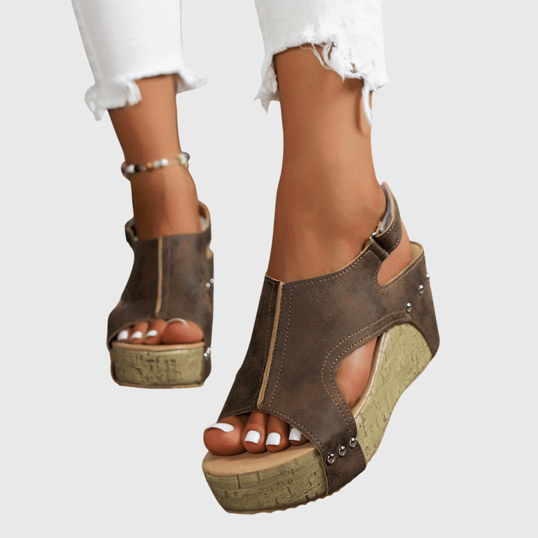 A woman in studded wedge sandals with an open front at a summer event.