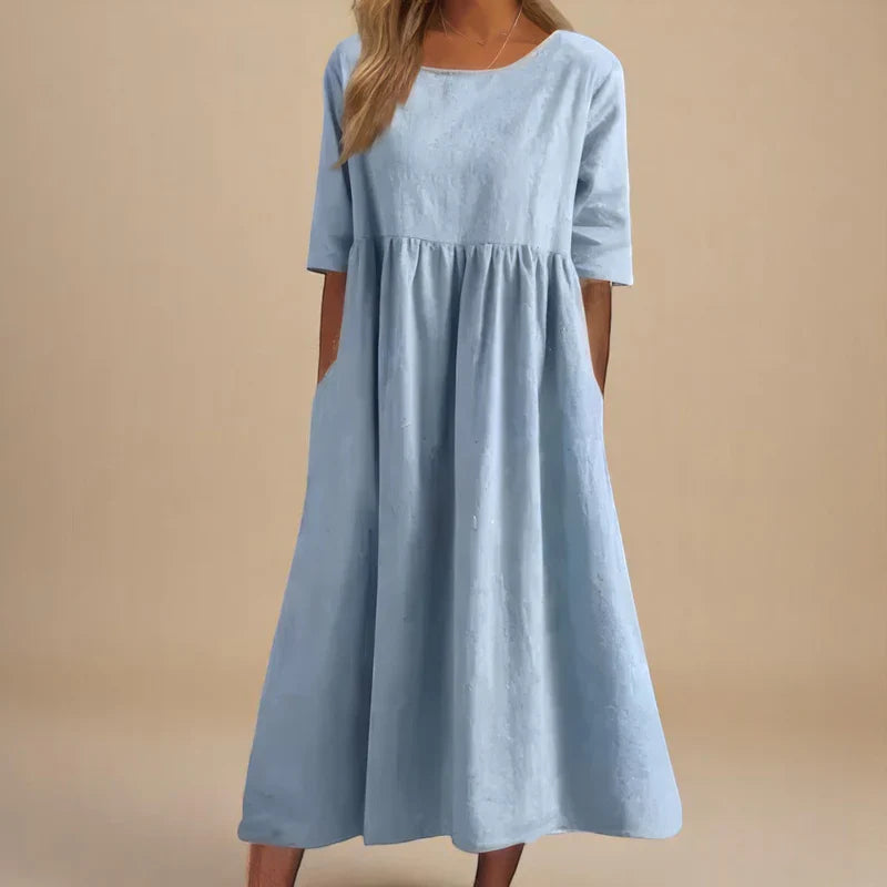 A woman wearing the Shannon flowing day dress with a gathered waist and elbow-length sleeves.