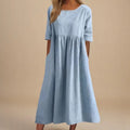 A woman wearing the Shannon flowing day dress with a gathered waist and elbow-length sleeves.
