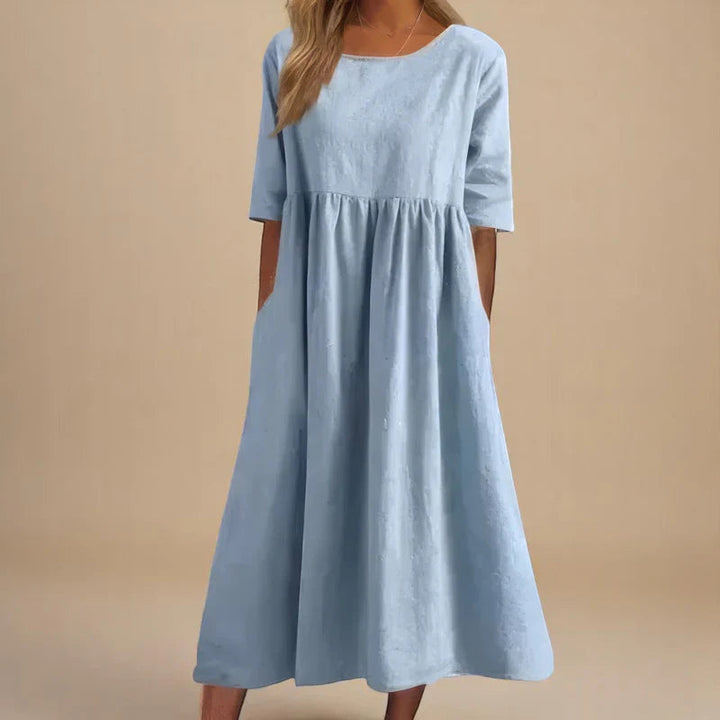 A woman wearing the Shannon flowing day dress with a gathered waist and elbow-length sleeves.