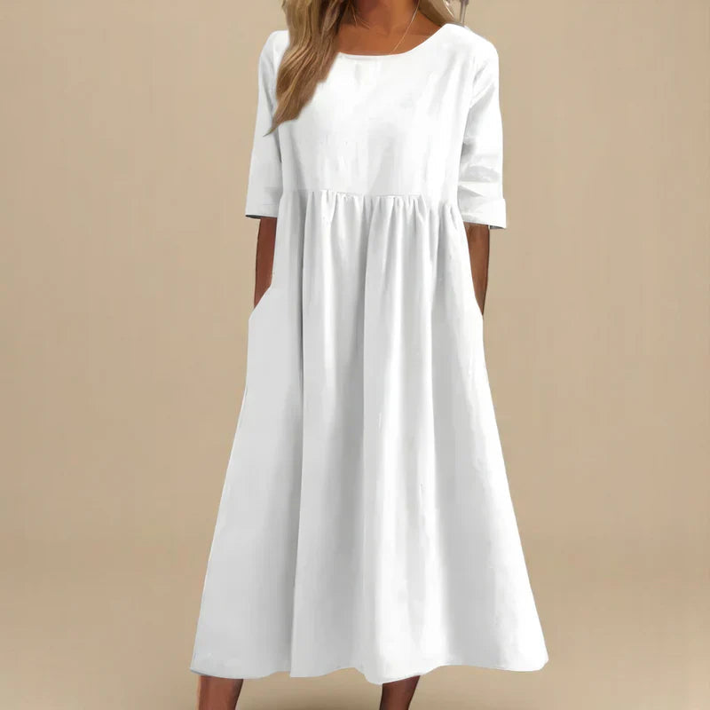 A woman wearing the Shannon flowing day dress with a gathered waist and elbow-length sleeves.