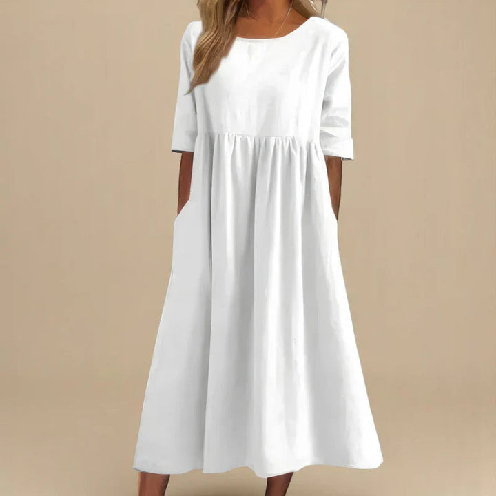 A woman wearing the Shannon flowing day dress with a gathered waist and elbow-length sleeves.