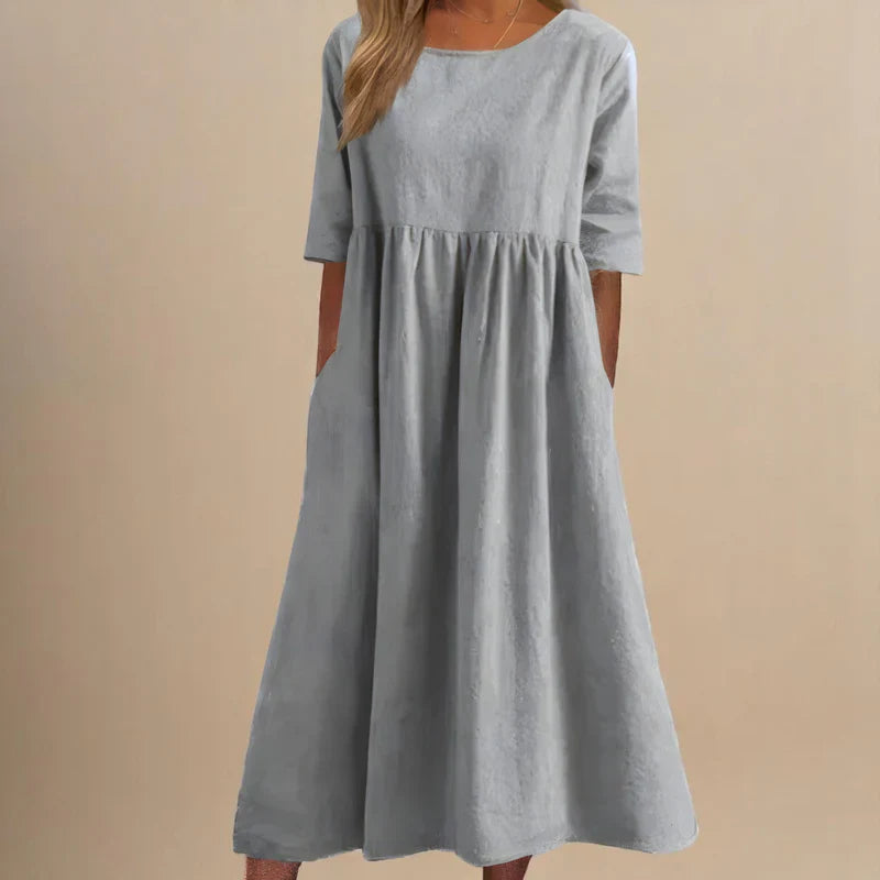 A woman wearing the Shannon flowing day dress with a gathered waist and elbow-length sleeves.