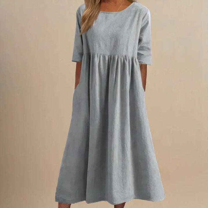 A woman wearing the Shannon flowing day dress with a gathered waist and elbow-length sleeves.