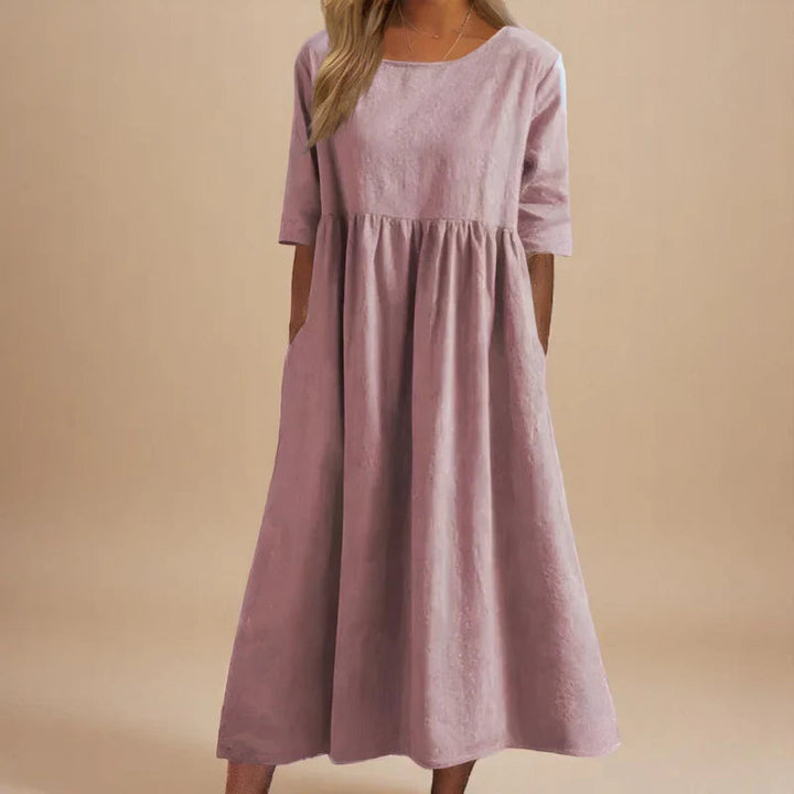 A woman wearing the Shannon flowing day dress with a gathered waist and elbow-length sleeves.