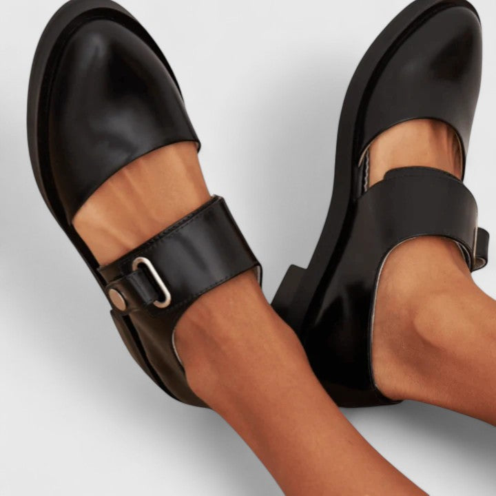 A woman wearing black Mary Jane shoes with an adjustable strap, comfortable on a busy day.