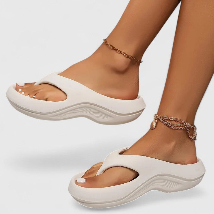 A woman in white slip-on sandals stepping out lightly, feet cushioned and supported.