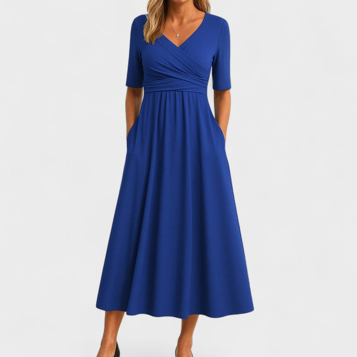 Woman wearing a royal blue mid-calf wrap dress with a crossover V-neckline, gathered waist, short sleeves and a gently flared skirt.