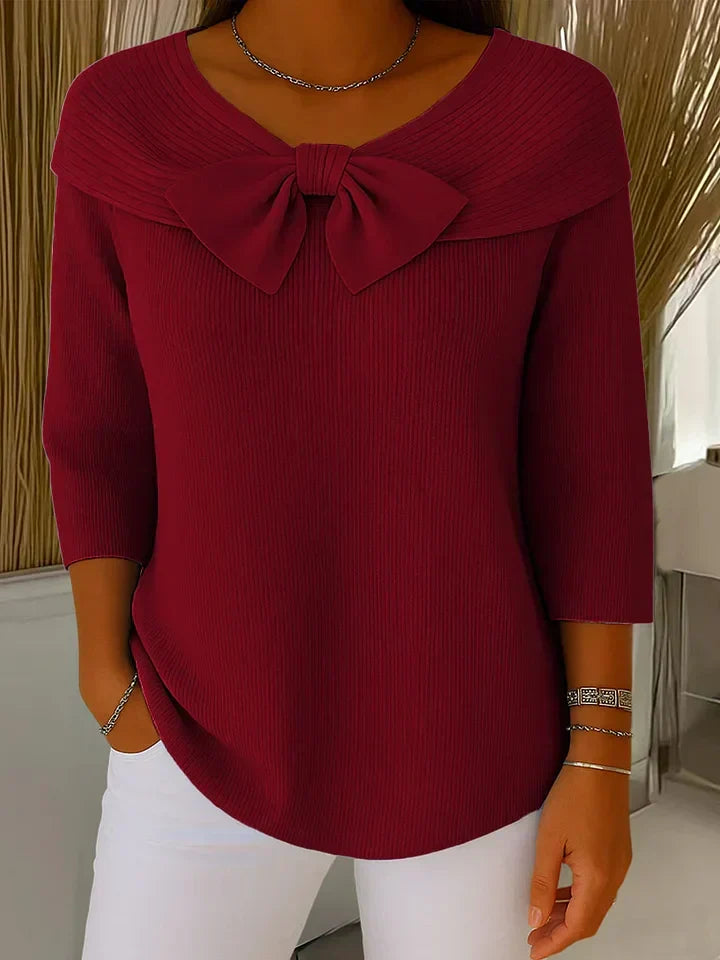 A woman wearing a shaped sweater with a soft bow detail, styled for a coffee date.