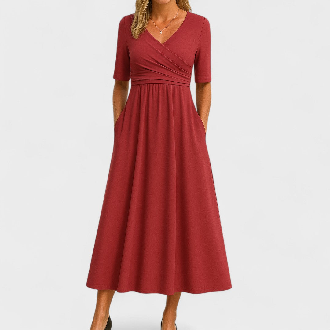 Woman wearing a royal blue mid-calf wrap dress with a crossover V-neckline, gathered waist, short sleeves and a gently flared skirt.