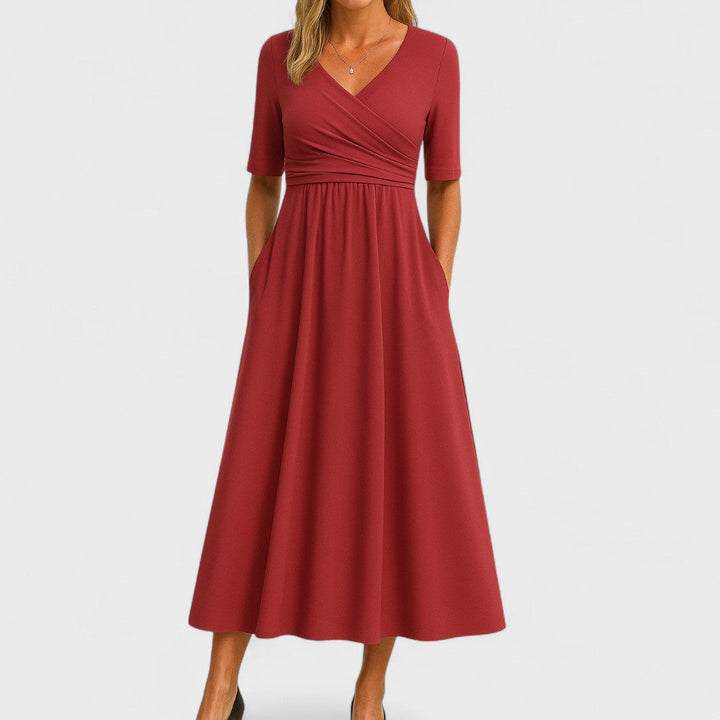 Woman wearing a royal blue mid-calf wrap dress with a crossover V-neckline, gathered waist, short sleeves and a gently flared skirt.