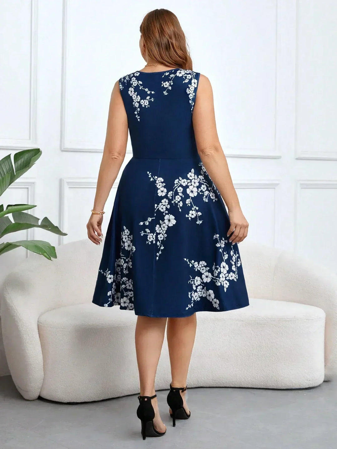 A woman wearing a sleeveless navy wrap dress with white floral print, the skirt flowing as she moves.
