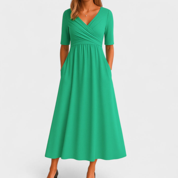 Woman wearing a royal blue mid-calf wrap dress with a crossover V-neckline, gathered waist, short sleeves and a gently flared skirt.