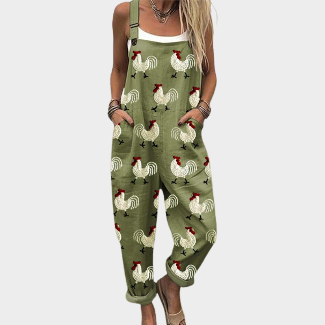 Woman wearing relaxed olive green overalls with a playful hen and cockerel print, side pockets and adjustable straps
