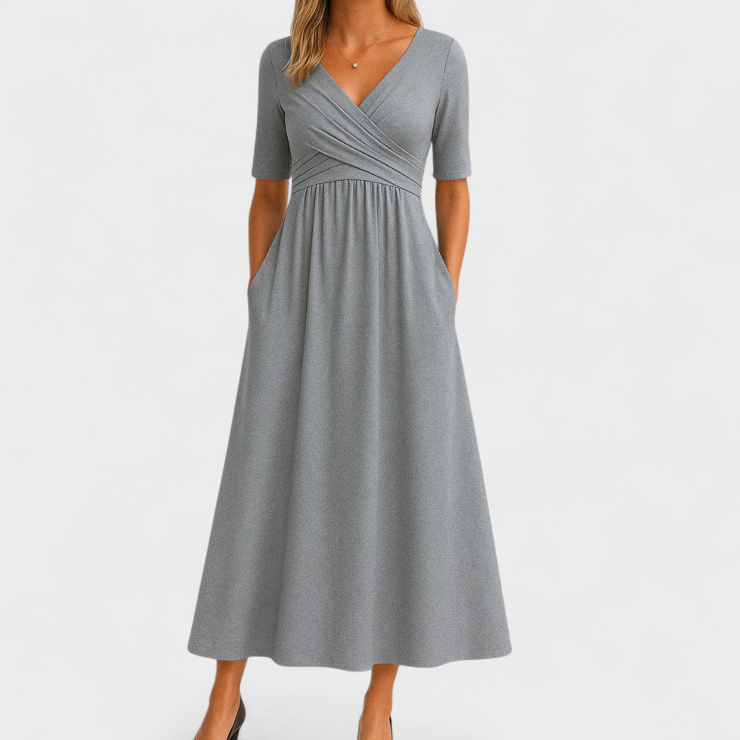 Woman wearing a royal blue mid-calf wrap dress with a crossover V-neckline, gathered waist, short sleeves and a gently flared skirt.