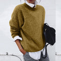 A woman wearing a soft mustard round-neck sweater with an elegant modern shape, relaxed and warm.