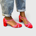A woman wearing berry red heels with an ankle strap, stepping out in a confident evening look.