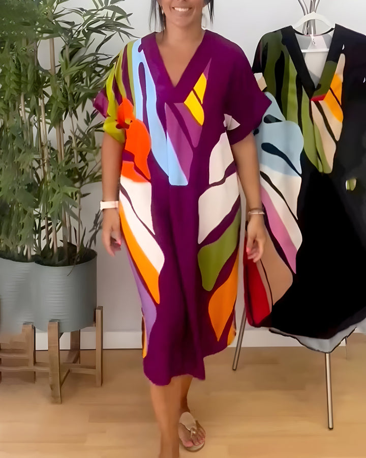A woman wearing a colourful abstract print dress with a V-neckline and short sleeves.
