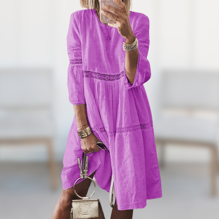 Woman wearing the Megan™ elegant summer dress with a round neckline and flowing silhouette, standing outdoors on a sunny day.