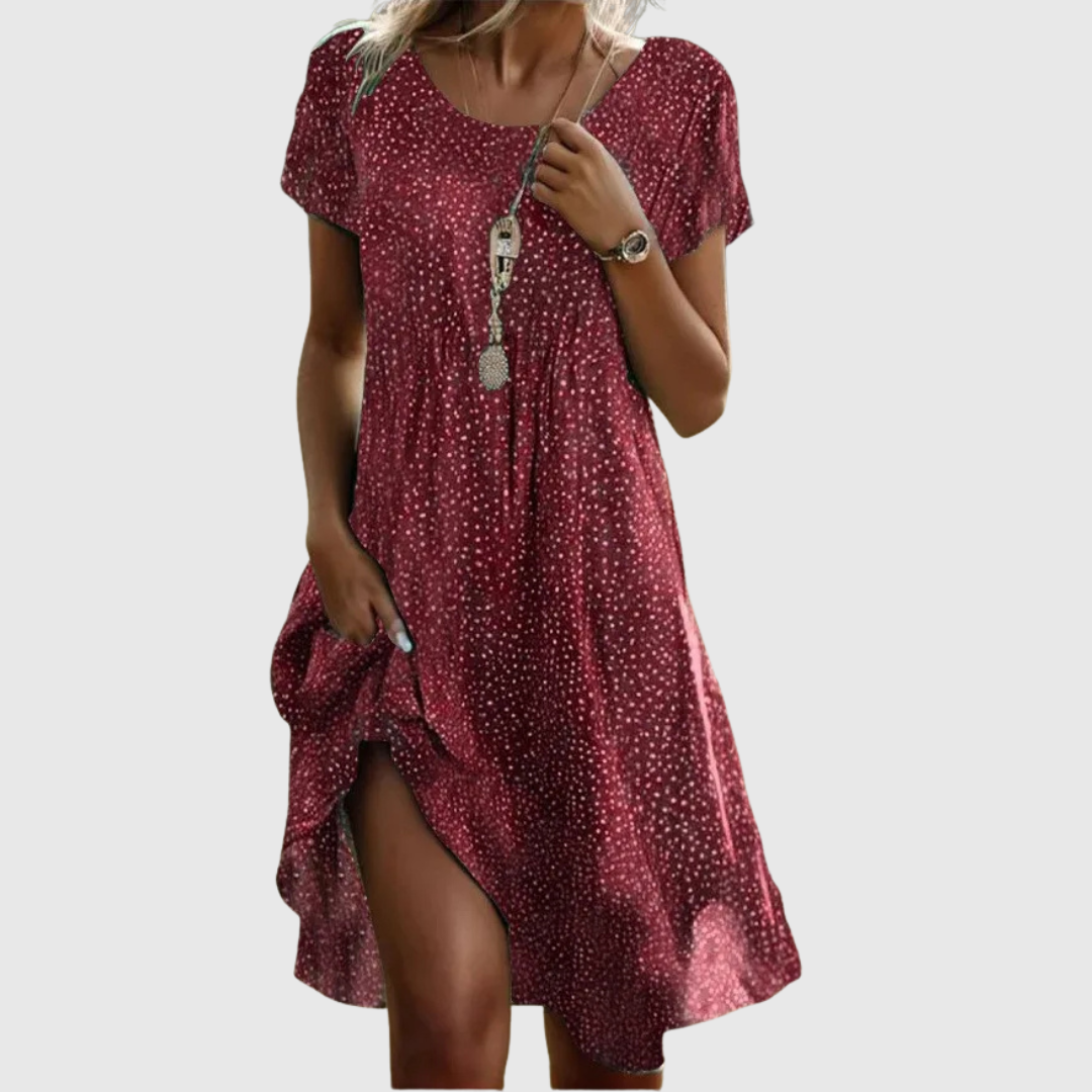 Woman wearing the Cynthia speckled summer dress in green, smiling in the sunshine outdoors.