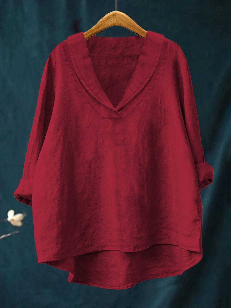 A woman wearing an elegant plain summer blouse with a flowing drape, styled with pants.