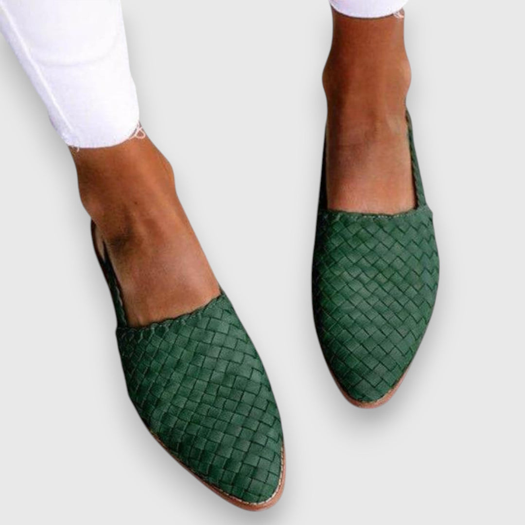 A woman wearing warm brown woven pointed-toe slingback flats with white cropped pants.