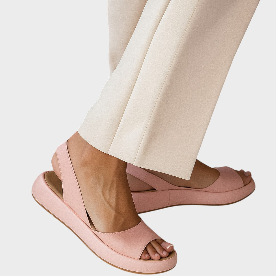 A woman walking gracefully in lightweight orthopaedic sandals with an adjustable strap on a sunny day.