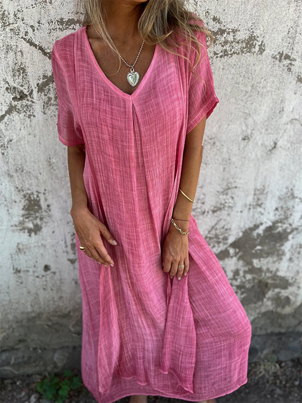 Woman wearing the Andrea™ flowing V-neck dress with short sleeves, standing relaxed in warm sunlight.